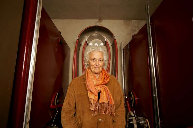 Anne-Claude Leflaive - Domaine Leflaive. Anne-Claude stands in her winery, the first time she has been photographed there; in fact the first time she has let anyone photograph in there at all. Above her head the pipe holder forms a crown, befitting the queen of white wine burgundy. The two vats at her sides are vats 4 and 5 and represent her 5 premier cru, and 4 grand cru, holdings.